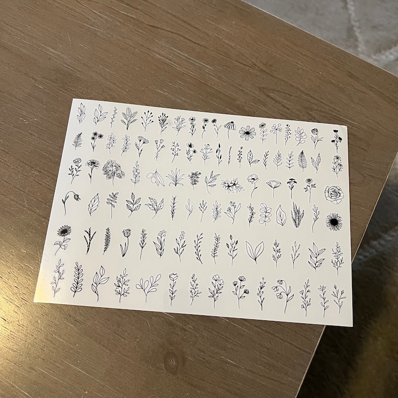 May include: A sheet of black and white floral and leaf illustrations. The sheet is divided into rows and columns, with each illustration separated by a small amount of space. The illustrations are simple and delicate, and they would be perfect for use in a variety of crafting projects.
