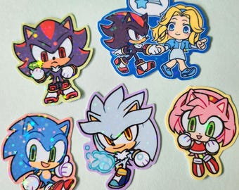May include: A collection of six holographic stickers featuring characters from the Sonic the Hedgehog video game series. The stickers showcase Sonic, Shadow, Amy, Silver, and other characters in vibrant colors and dynamic poses.