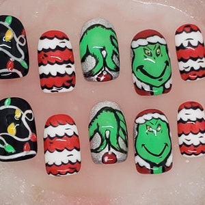 May include: Set of ten fake nails with Christmas lights, Grinch, and red and white striped designs.
