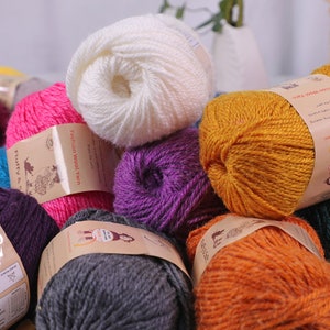 May include: Assortment of colorful yarn balls in various shades of pink, purple, white, orange, yellow, gray, and teal. The yarn is labeled "Fashion Wool Yarn" and "Fluffy & Soft".