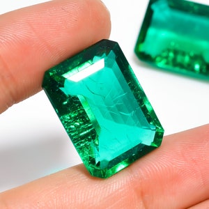 Pode incluir: Duas pedras preciosas de cor verde esmeralda cortadas em forma retangular com bordas chanfradas. As pedras preciosas são facetadas e têm um alto nível de clareza.