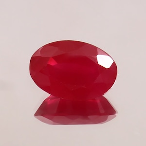 Op de afbeelding: Een dieprode ovale edelsteen met een facetgeslepen vorm.