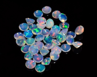 Pode incluir: Um grupo de gemas de opala iridescente em vários tons de azul, verde e rosa. As gemas são redondas e têm um acabamento liso e polido.