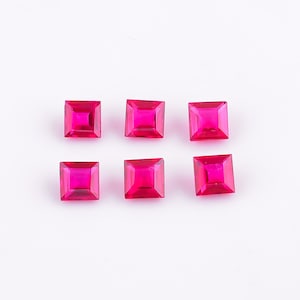 May include: Six square-shaped, bright pink gemstones on a white background.