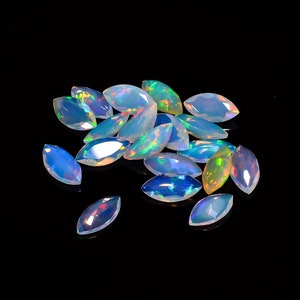 Può includere: Un gruppo di pietre preziose di opale a forma di marquise in varie tonalità di blu, verde e bianco. Le pietre preziose sono disposte in un mucchio sciolto su uno sfondo nero.