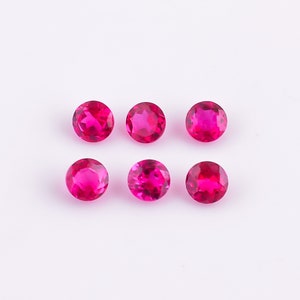 Può includere: Sei pietre preziose rotonde di colore rosa brillante su uno sfondo bianco.