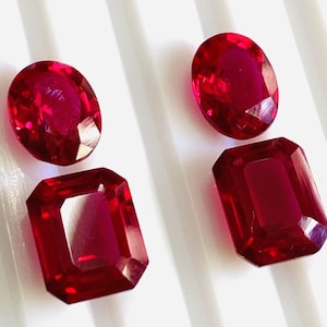 Peut inclure: Trois pierres précieuses de rubis rouges, une ovale et deux rectangulaires, sur un fond blanc.