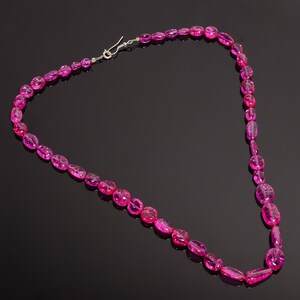 May include: A pink gemstone necklace with a silver clasp. The necklace is made of oval-shaped beads.