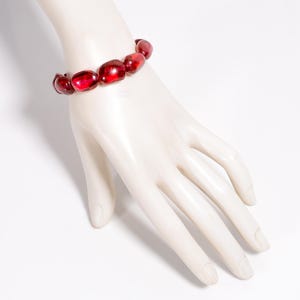 May include: A red beaded bracelet with oval-shaped beads.