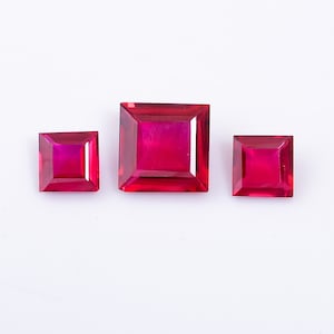 Peut inclure: Trois pierres précieuses carrées de couleur rouge de différentes tailles. Les pierres précieuses sont taillées à facettes et ont une finition brillante et polie.