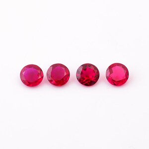 May include: Four round, red gemstones on a white background.