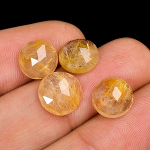 May include: Four round, faceted, golden-yellow gemstones with gold inclusions. The gemstones are translucent and have a shiny, polished finish.