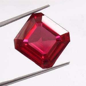 May include: A deep red emerald cut gemstone with a square shape.