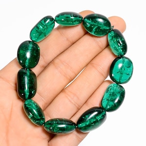 Op de afbeelding: Een groene edelsteen armband met ovale kralen. De armband is gemaakt van natuurlijke groene edelstenen en is geregen op een doorzichtig elastisch koord.