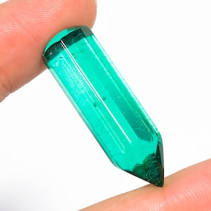 Op de afbeelding: Een levendige groene kristallen punt met een gefacetteerde, langwerpige vorm. De kristal is doorschijnend en heeft een lichte glans.