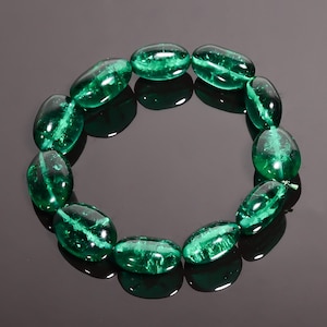 Op de afbeelding: Een groene edelsteen armband met ovale kralen. De kralen zijn doorschijnend en hebben een licht troebele uitstraling.