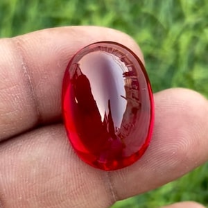 Può includere: Una pietra preziosa rossa liscia di forma ovale con una finitura lucida.