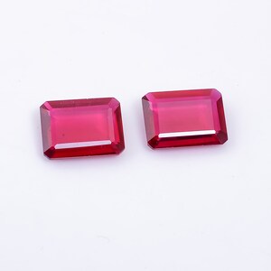 May include: Two red rectangular gemstones with a faceted cut.