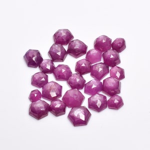 May include: A collection of 20 faceted pink ruby gemstones. The stones are cut in a unique shape with many facets. The stones are all different sizes and shapes, but they are all a beautiful pink color.