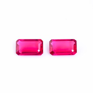 May include: Two vibrant pink rectangular gemstones with a faceted cut.