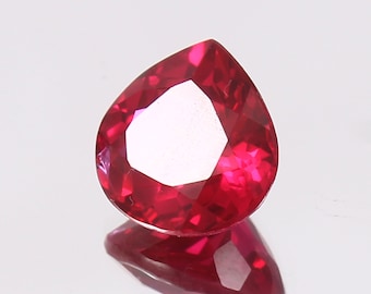 Puede incluir: Una piedra preciosa de color rojo intenso en forma de pera con un corte facetado.