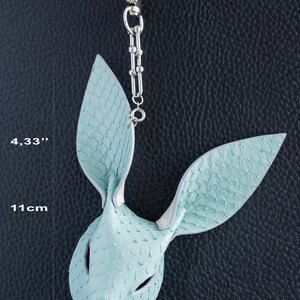 May include: A light blue leather bunny mask pendant with a silver chain. The mask is 11 cm long and features a textured, scale-like pattern. The pendant hangs from a silver chain.