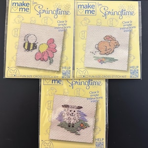 May include: A white ceramic mug with a black handle and the text "But First, Coffee" in a bold, black font. The mug is set against a blurred background, suggesting a cosy setting.