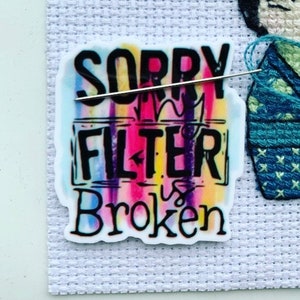 May include: A colorful sticker with the text "SORRY MY FILTER IS BROKEN" in black lettering. The sticker has a rainbow background with a white border.