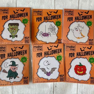 May include: Six Make Me For Halloween fun size cross stitch kits in orange packaging. Each kit features a unique design: a green monster, a purple spider with a web, a white ghost with the text Boo, a witch on a broom, a bat, and a jack-o'-lantern.