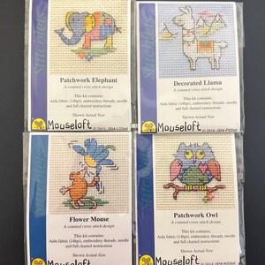 May include: Four cross-stitch kits featuring animal designs. The kits include a patchwork elephant, a decorated llama, a flower mouse, and a patchwork owl. Each kit includes Aida fabric, embroidery threads, a needle, and instructions. The designs are colorful and whimsical.