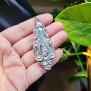 May include: A silver pendant made from a vintage spoon with an ornate floral design.