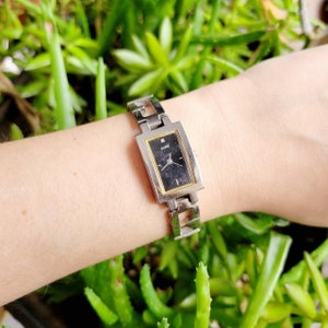 May include: A silver Guess watch with a black rectangular face and a silver metal band.