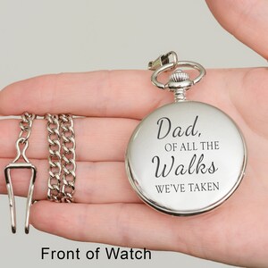May include: Silver pocket watch with a chain. The watch face has the inscription "Dad, of all the walks we've taken."