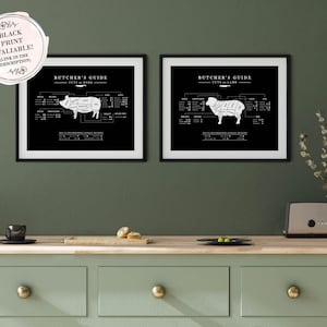 A black and white butcher poster of two framed pictures of lamb and pork on a green kitchen wall, hung over the countertop