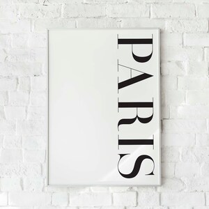 K&ouml;nnte beinhalten: Ein wei&szlig;er gerahmter Poster mit dem Wort "PARIS" in schwarzen vertikalen Buchstaben.