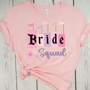 May include: Pink t-shirt with a castle graphic and the text "Bride Squad" in black.