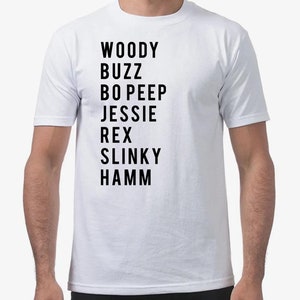 K&ouml;nnte beinhalten: Wei&szlig;es T-Shirt mit schwarzem Text, der die Namen der Charaktere aus der Toy Story-Reihe auflistet: Woody, Buzz, Bo Peep, Jessie, Rex, Slinky, Hamm.
