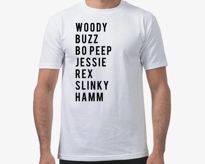 K&ouml;nnte beinhalten: Wei&szlig;es T-Shirt mit schwarzem Text, der die Namen der Charaktere aus der Toy Story-Reihe auflistet: Woody, Buzz, Bo Peep, Jessie, Rex, Slinky, Hamm.