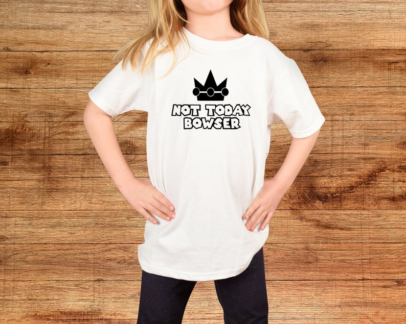 Puede incluir: Camiseta blanca con una corona negra y el texto "NOT TODAY BOWSER" impreso en la parte delantera.