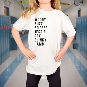 K&ouml;nnte beinhalten: Wei&szlig;es T-Shirt mit schwarzem Text, der "WOODY BUZZ BO PEEP JESSIE REX SLINKY HAMM" lautet