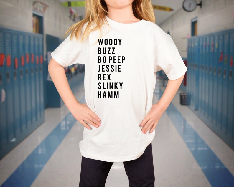 K&ouml;nnte beinhalten: Wei&szlig;es T-Shirt mit schwarzem Text, der "WOODY BUZZ BO PEEP JESSIE REX SLINKY HAMM" lautet