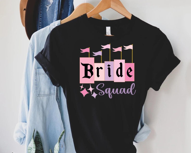 May include: Black t-shirt with a pink and purple castle graphic and the text "Bride Squad".