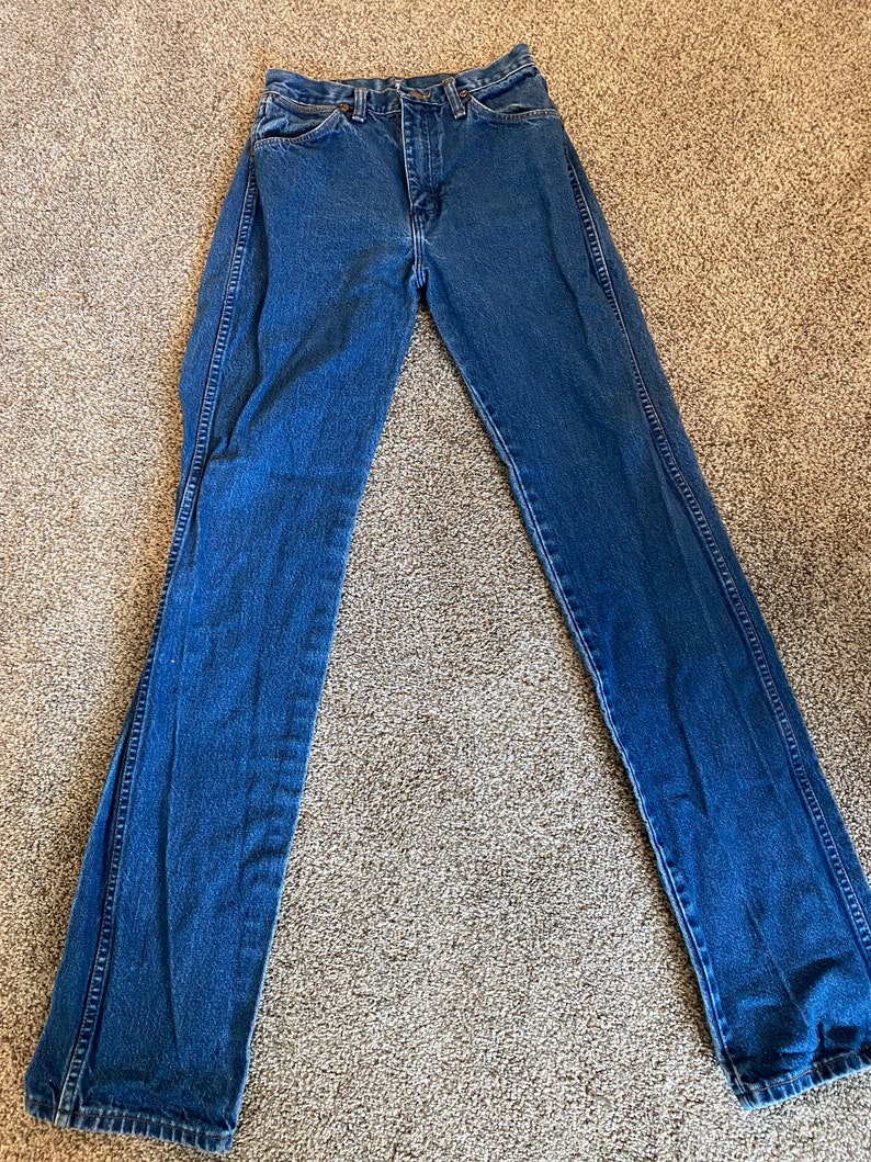 May include: A pair of blue denim jeans. The jeans have a classic five-pocket design, a button and zipper closure, and a straight leg fit. The denim is a medium wash, with visible stitching.