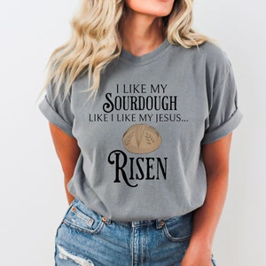 May include: Gray t-shirt with a graphic of a sourdough bread loaf and the text "I like my sourdough like I like my Jesus... Risen".