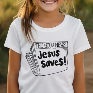 Pode incluir: Camiseta branca com um gr&aacute;fico preto e branco de uma manchete de jornal que diz "The Good News Jesus Saves!"