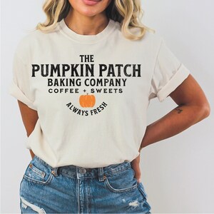 May include: A white t-shirt with the text "The Pumpkin Patch Baking Company Coffee + Sweets Always Fresh" and a small orange pumpkin graphic.