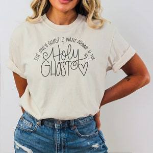 May include: White t-shirt with black text that reads "The only ghost I want around is the Holy Ghost" with a heart.