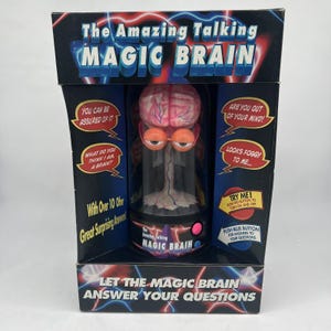 May include: A black box with a pink and white brain in a glass jar. The box has the text "The Amazing Talking Magic Brain" and "Let the Magic Brain Answer Your Questions".