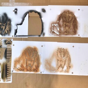Puede incluir: Una colecci&oacute;n de plantillas art&iacute;sticas con varios dise&ntilde;os. Las plantillas incluyen un b&uacute;ho, patrones geom&eacute;tricos y flechas direccionales. La obra de arte est&aacute; creada con pintura en aerosol sobre papel blanco, con tonos marrones y negros.