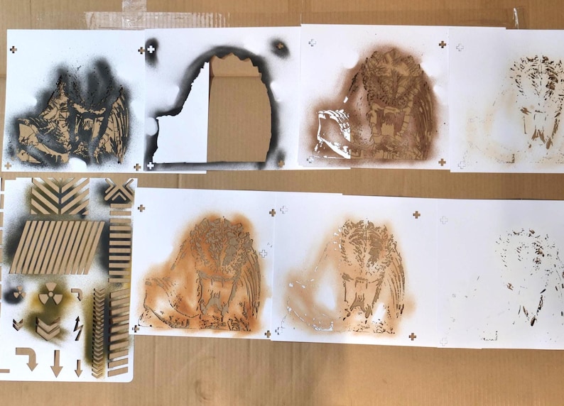 Puede incluir: Una colecci&oacute;n de plantillas art&iacute;sticas con varios dise&ntilde;os. Las plantillas incluyen un b&uacute;ho, patrones geom&eacute;tricos y flechas direccionales. La obra de arte est&aacute; creada con pintura en aerosol sobre papel blanco, con tonos marrones y negros.